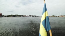 Sweden Flag Waving In The Wind On Ship Aft Stern Feed Flagpole Sailing In Stockholm City Center Harbour