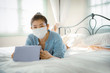 © stockphoto mania - woman with protection mask in hand lying on sofa bed in home living room chatting to internet device