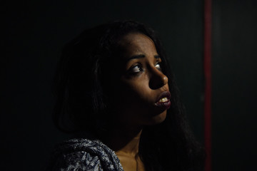 Wall Mural - young African woman posing at studio, face with hand portrait over dark background	