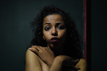 Wall Mural - young naked African woman posing at studio, face with hand portrait over dark background	