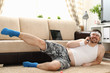© H_Ko - Young handsome fitness man lies on fat mat with overweight performs exercises and smiles. Calls on phone and tells how he at home began engage in fitness Monday to lose weight flirting and happy