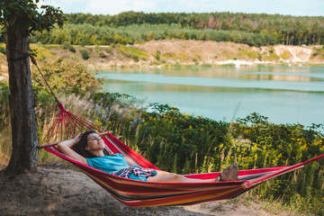 Wall Mural - woman laying on hammock enjoying the view of summer lake