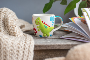 Kid's cup and books on a wooden table. Childhood