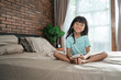 © Odua Images - smile young girl holding phone sitting on the bed