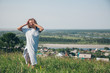 © aaalll3110 - a girl in a loose dress with loose hair walks in a meadow. Village houses, forest and river as background. The concept of summer, warmth, freedom, village life, sunburn