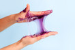 © misskaterina - Young girl hands with sticky purple slime on blue background, liqiud wax for depilation, conceptual flyer banner with copy space, antistress relax, modern kids hobby