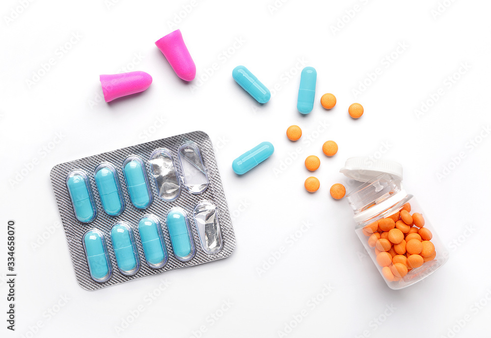 Ear plugs and sleeping pills on white background