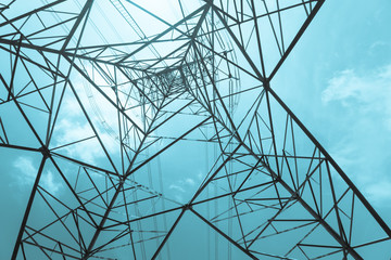 Abstract pattern from bottom view of high voltage pole power transmission tower with clear sky sunshine day background in monochrome tone. Green energy, environmental conservation concept.