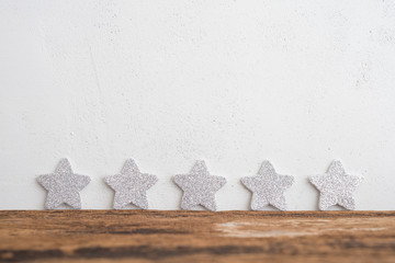 White glitter five stars shape put on wooden table and white background. Services rating customer experience, satisfaction, feedback score and customer evaluation concept.