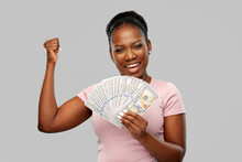 Finance, Currency And People Concept - Happy African American Young Woman Holding Hundreds Of Dollar Money Banknotes Celebrating Success Over Grey Background