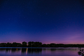 Wall Mural - trees reflecting on peaceful lake under beautiful starry sky at night
