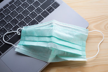 Face mask, Medical mask, Surgical mask on laptop,  Wooden texture background, Close up shot, Selective focus, Prevention from covid19, Coronavirus, Bacteria, Healthcare