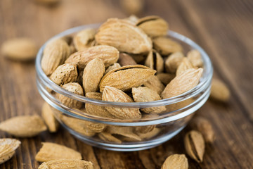 Canvas Print - Roasted Almonds (in shell) on a wooden table (selective focus)