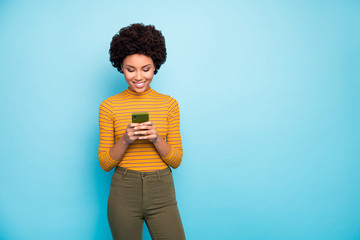 Poster - Photo of funny dark skin lady hold telephone hands reading new post comments popular influencer wear yellow striped jumper green pants isolated blue color background