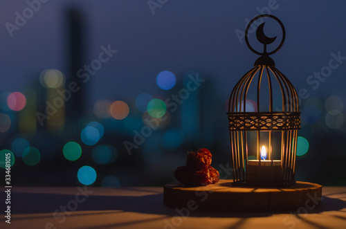 Fotomural Lantern that have moon symbol on top and dates fruit put on wooden tray with colorful city bokeh lights for the Muslim feast of the holy month of Ramadan Kareem