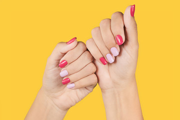 Closeup photo of two female hands and fingers manicured. Fingernails with fresh professional spring or summer naildesign isolated on bright yellow  background. Painted nails with modern gel-polish.