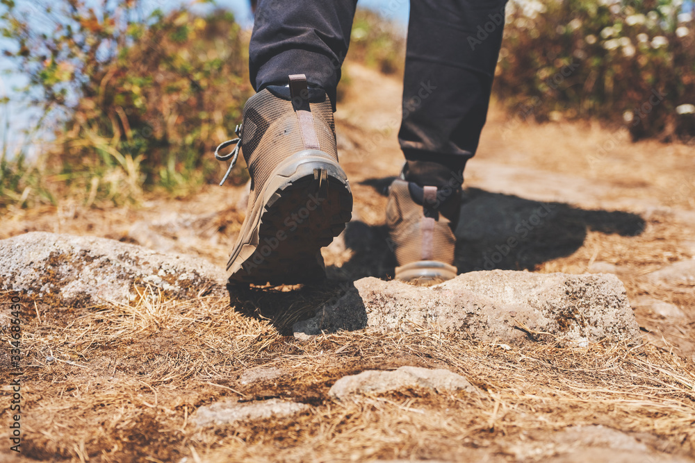 Closeup image of a woman hiking with trekking boots on the top of mountain - obrazy, fototapety, plakaty 