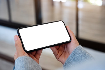 Mockup image of a woman holding mobile phone with blank white desktop screen