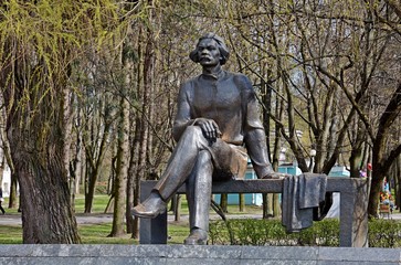 Monument to Maxim Gorky in Minsk. Maxim Gorky Park. The bench is mounted on a low granite pedestal. On the bench is a writer. A thoughtful look looks into the distance.