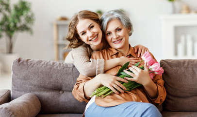 Wall Mural - happy woman hugging aged mother with flowers.