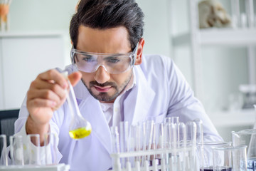 Wall Mural - attractive happiness scientist man lab technician assistant analyzing sample in test tube at laborat