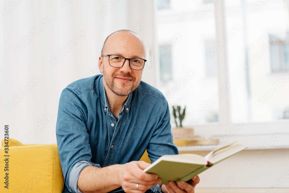 Happy friendly man wearing glasses with a book - obrazy, fototapety, plakaty 