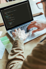 Cropped view of developer working with laptop at table in coworking space