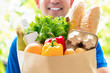 Smiling delivery man holding a grocery bag ready to deliver to the customer at home