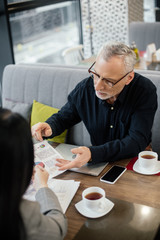 Wall Mural - selective focus of businessman holding papers and talking with businesswoman in cafe