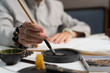  a man dips a brush for calligraphy in ink