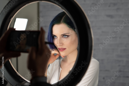 Young Beautiful Girl With Professional Makeup Blue Hair And Perfect Skin Sits In Studio In Front Of Ring Light Lamp Posing For Social Media Beauty Blog Copy Space Kaufen Sie Dieses