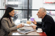 © LIGHTFIELD STUDIOS - side view of businessman and smiling asian businesswoman talking in cafe