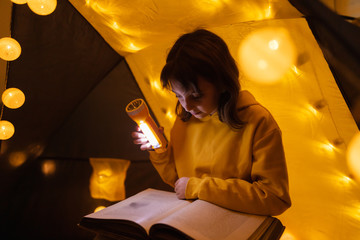 Wall Mural - young girl student learning and homeschooling in a home made tent with glowing light balls.