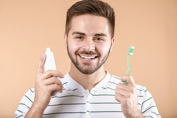 Wall Mural - Happy smiling young man with tooth brush and paste on color background