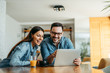 © bnenin - Couple looking at laptop computer together, at home, front view, portrait.