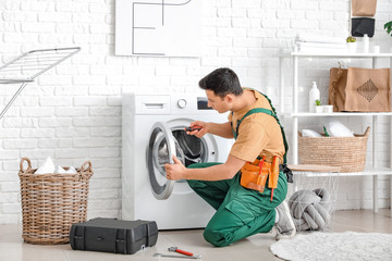 Worker repairing washing machine in laundry room