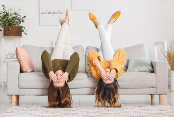 Sticker - Young women in warm sweaters lying on sofa at home