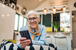 © bnenin - Happy senior woman reading text message on smart phone, copy space.