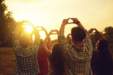 Heart sign with hands of a group of people at sunset.