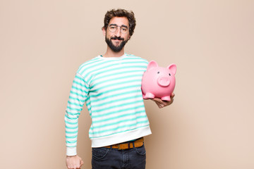 Poster - young cool man holding a piggy bank against clean wall
