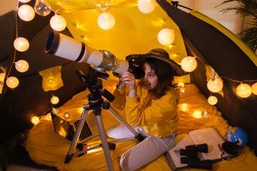 Wall Mural - small girl using telescope at home living room in a tent.