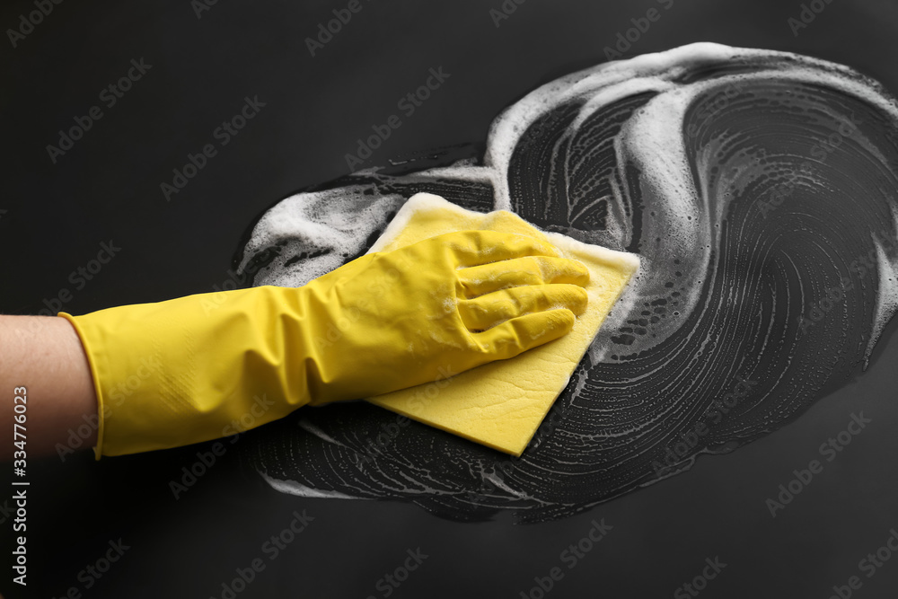 Hand of woman cleaning dark table