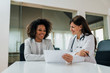 © bnenin - Good news! Smiling female patient and doctor looking at paper document.