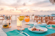 © icemanphotos - Luxury dinner food, cocktails on wooden table, with beautiful tropical resort, outdoor restaurant background, sunset time summer holiday and romantic vacation concept, luxury travel and lifestyle