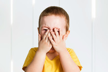 Crying Baby Boy In A Yellow Shirt Covers His Face With Hands And Shouts, Tears