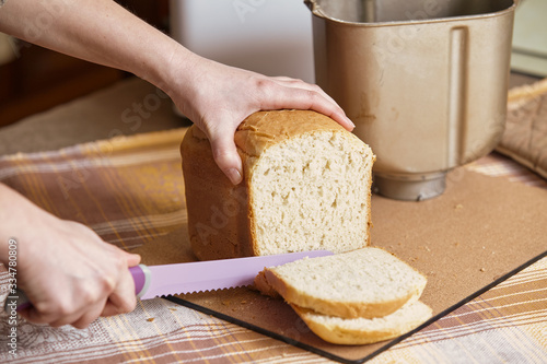 Fotografía Hostess cuts loaf of bread with big knife