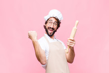 Young Crazy Baker Man With A Cook Tool Against Pink Wall