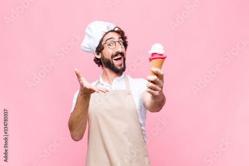 Fotografía young crazy chef man with an ice cream against pink wall