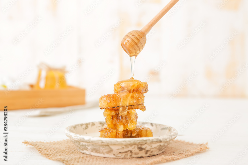 Honey dripping from dipper on tasty honeycombs