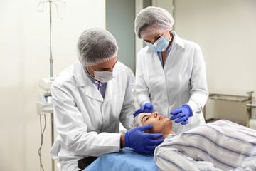 Sticker - Doctor and nurse preparing female patient for cosmetic surgery in clinic